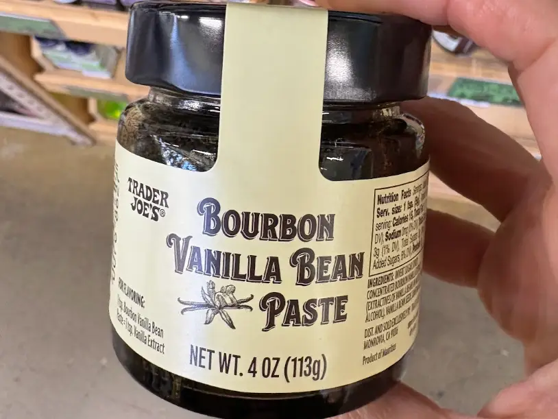 A hand holding Trader Joe's bourbon vanilla bean paste.