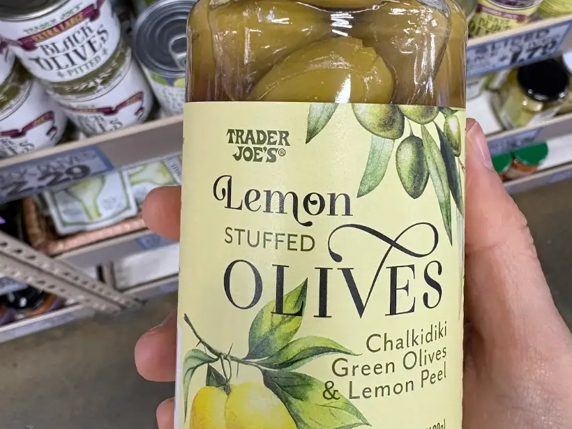 A hand holding lemon-stuffed olives at Trader Joe's.