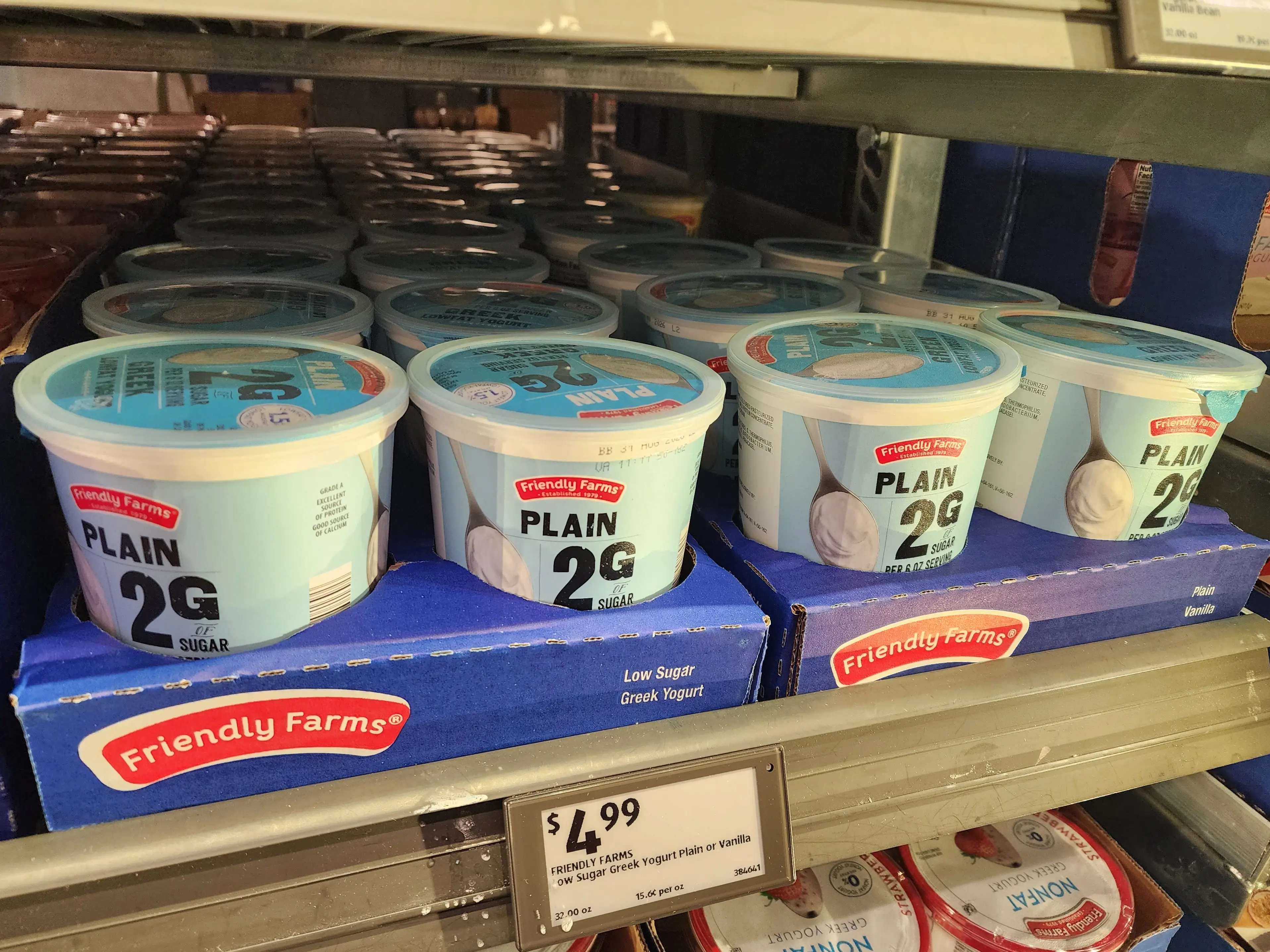 Several containers of Friendly Farms plain Greek yogurt sitting on a shelf at Aldi.